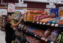 A woman takes a product off a grocery store shelf
